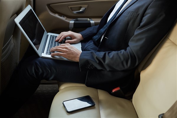 businessman-working-on-laptop-in-the-car-VFXJ4JS